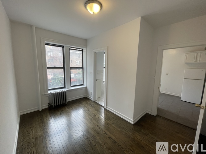 A room with wood flooring and a window with a view of a building outside.