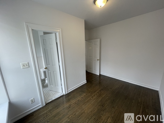 A room with a white door and a wooden floor.