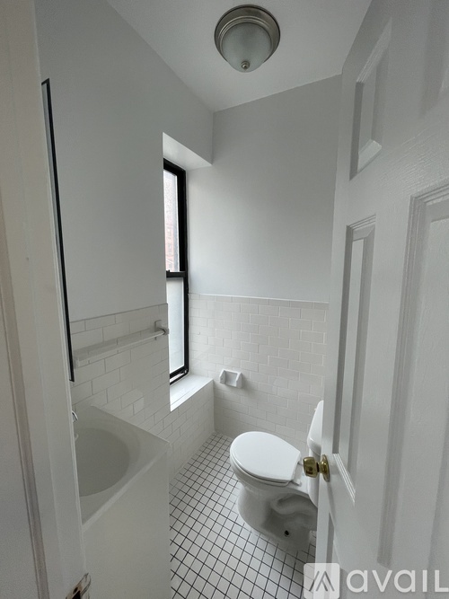 A white toilet in a small bathroom with a window.