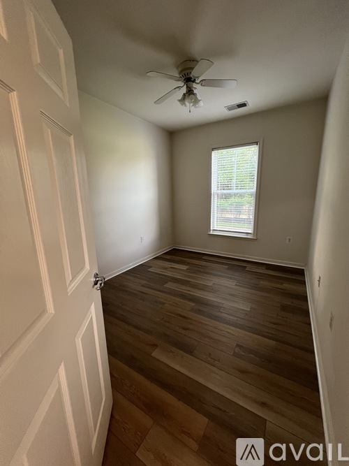 A room with a ceiling fan and wooden flooring.