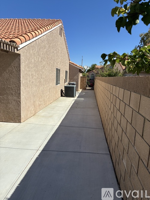 A narrow alley with a wall on one side and a building with a red tile roof on the other.