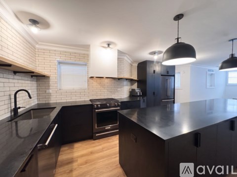 A modern kitchen with black countertops and a brick backsplash.