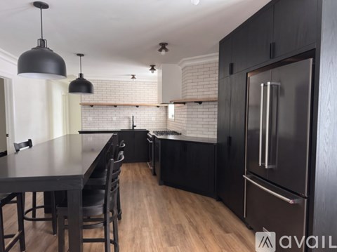 A kitchen with black cabinets and a wooden floor.