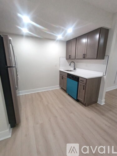 A kitchen with a refrigerator, sink, and cabinets.
