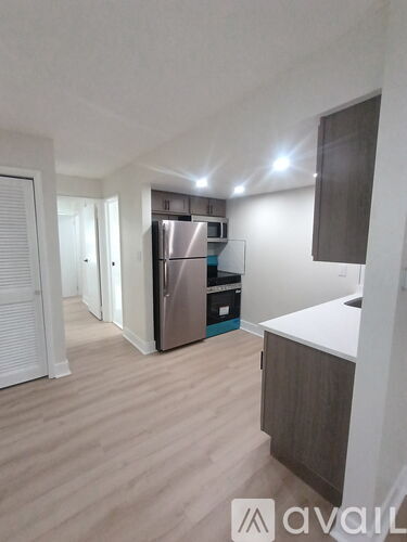 A kitchen with a refrigerator, sink, and cabinets.