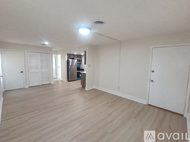 A spacious room with wooden flooring and white walls.
