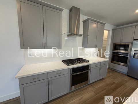 A modern kitchen with grey cabinets and stainless steel appliances.