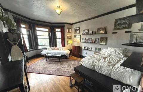 A bedroom with a bed, a couch, and a rug.
