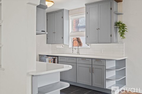 A kitchen with grey cabinets and a white countertop.