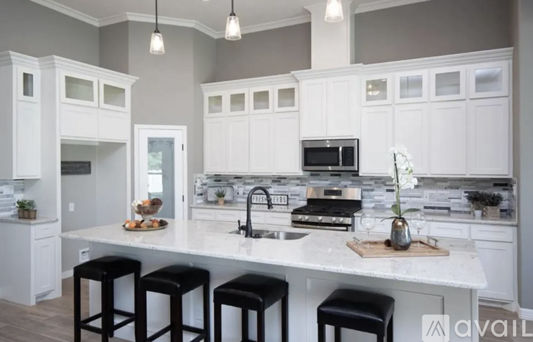 A kitchen with white cabinets and a marble countertop.