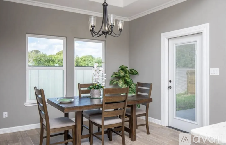 A dining room with a table set for four and a chandelier hanging from the ceiling.