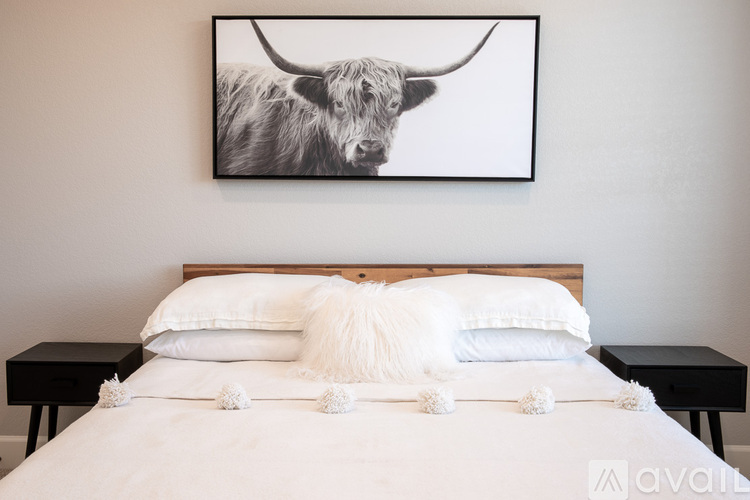 A bed with white bedding and a picture of a bull above it.