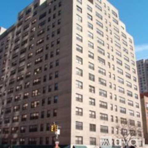 A tall building with many windows stands in a city.
