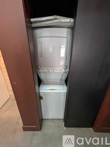 A white toilet is installed in a small space under a brown cabinet.