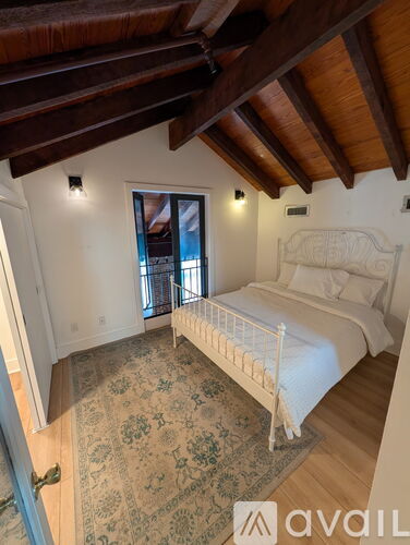 A bedroom with a bed, a rug, and a window.