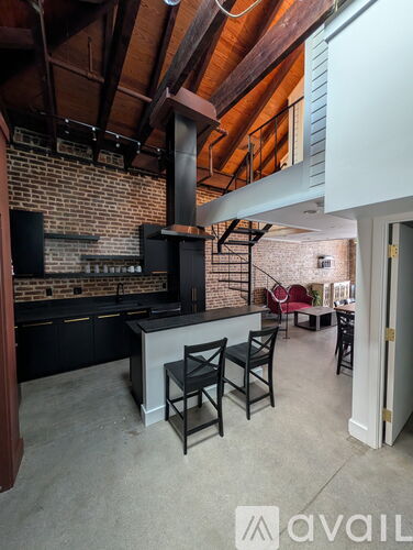 A kitchen with a brick wall and a black stove top oven.