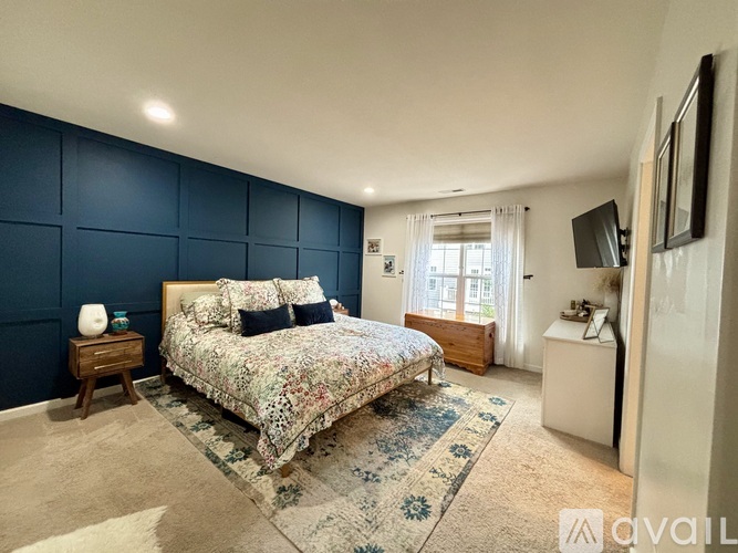A bedroom with a floral bedspread and a wooden nightstand.