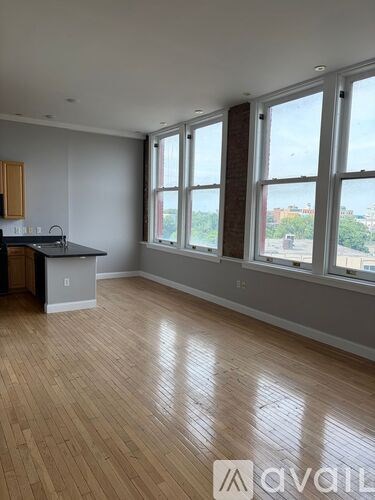 A room with wooden floors and a kitchen area with a sink and stove.