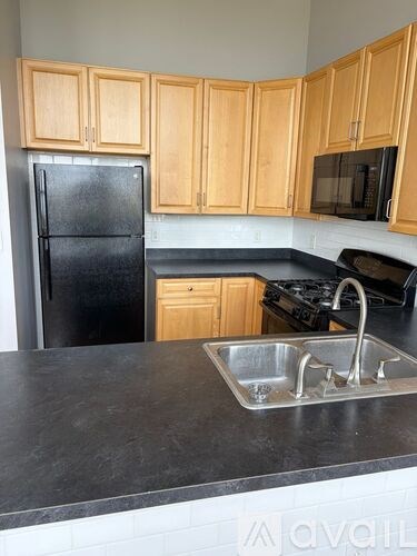 A kitchen with wooden cabinets and a black refrigerator.