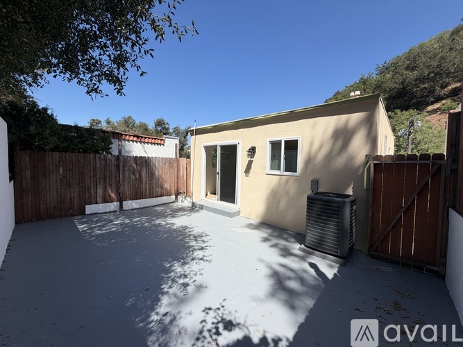 A backyard with a tan house, a fence, and a tree.