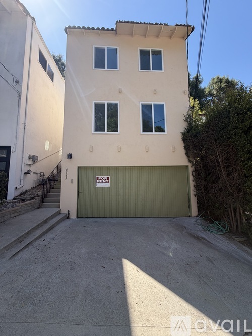 A two-story building with a garage door and a sign that says "For Sale".