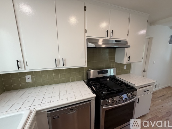 A kitchen with white cabinets and a stainless steel range hood.