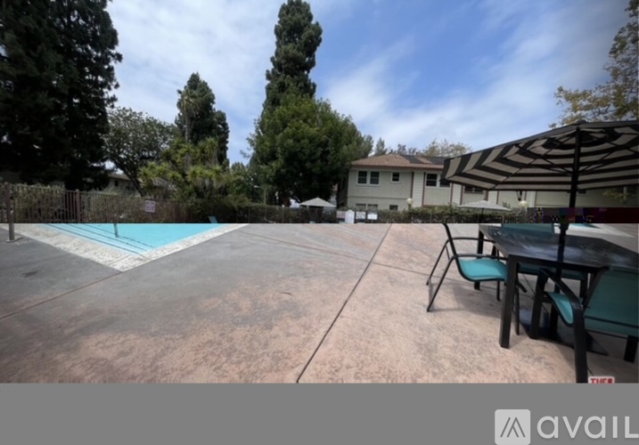 A pool area with a table and chairs in front of a house.