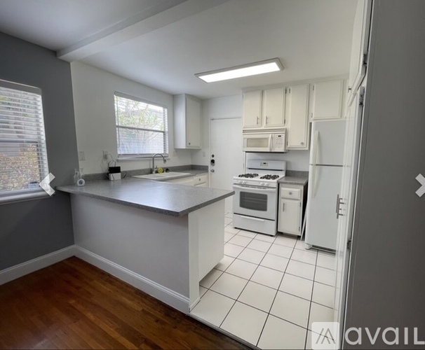 A kitchen with white appliances and wooden floors.