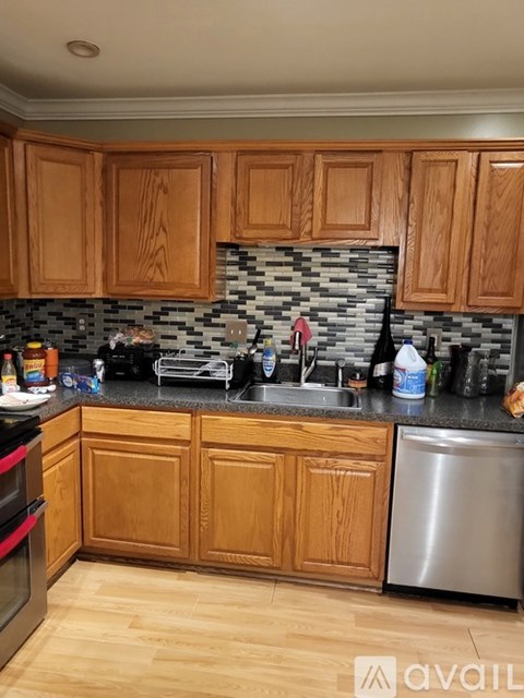 A kitchen with wooden cabinets and a black granite backsplash.