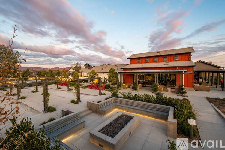 A modern building with a red and orange facade is surrounded by a landscaped courtyard.