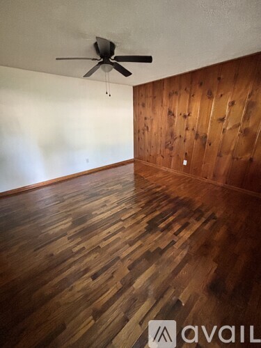 A room with wooden flooring and a ceiling fan.