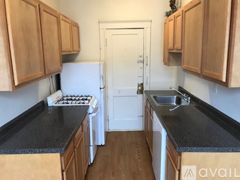 A kitchen with wooden cabinets and black countertops.