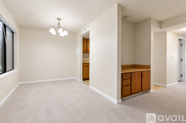 A spacious room with a carpeted floor and a chandelier hanging from the ceiling.