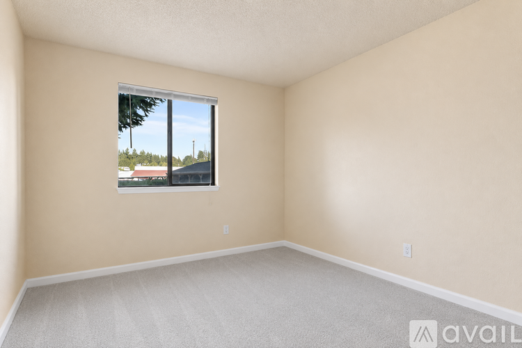 A room with a window showing a view of a street and buildings outside.