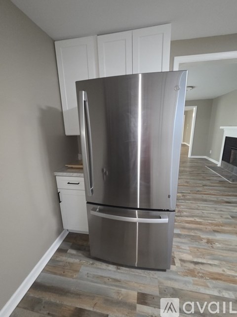 A stainless steel refrigerator in a kitchen with wooden flooring.