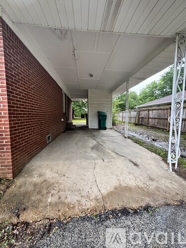 A covered walkway with a brick wall on one side and a metal fence on the other.