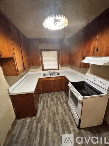 A kitchen with wooden cabinets and a white stove top oven.
