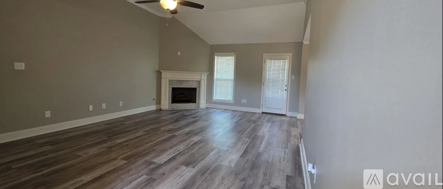 A spacious room with wood flooring and a fireplace.