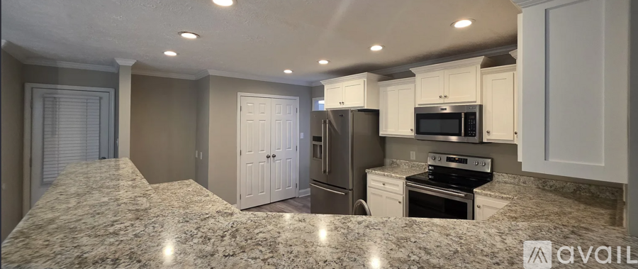 A kitchen with granite countertops and white cabinets.