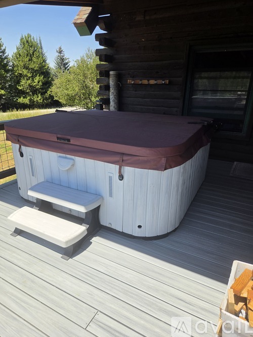 A hot tub on a wooden deck outside a cabin.
