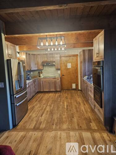 A kitchen with wooden floors and a refrigerator on the left.