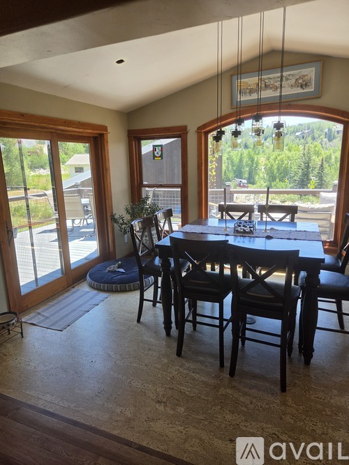 A dining room with a table and chairs and a view of the backyard.