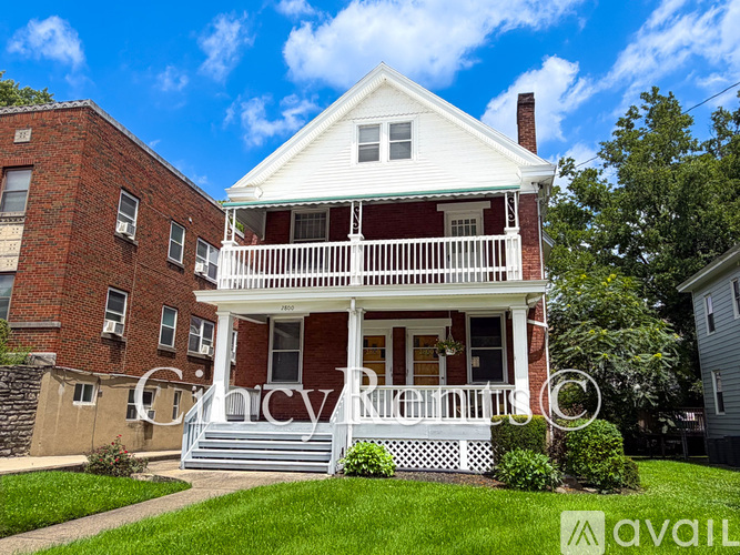 A two-story house with a white front porch and a red brick exterior.