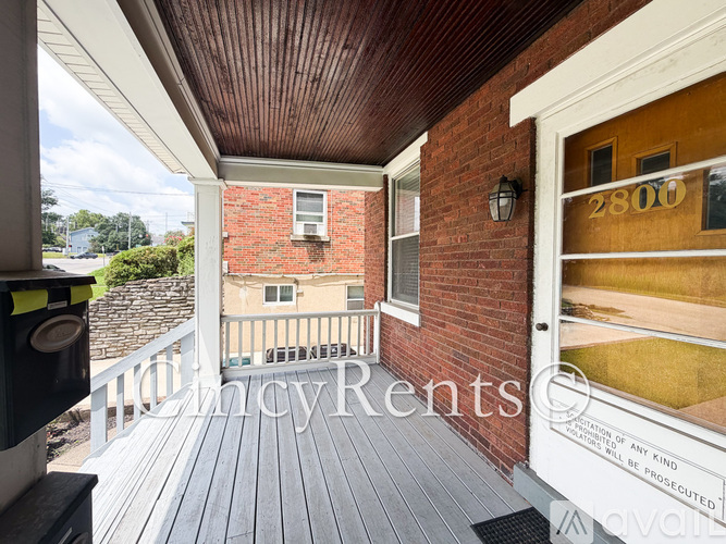 A balcony with a wooden floor and a brick wall with a door numbered 2800.