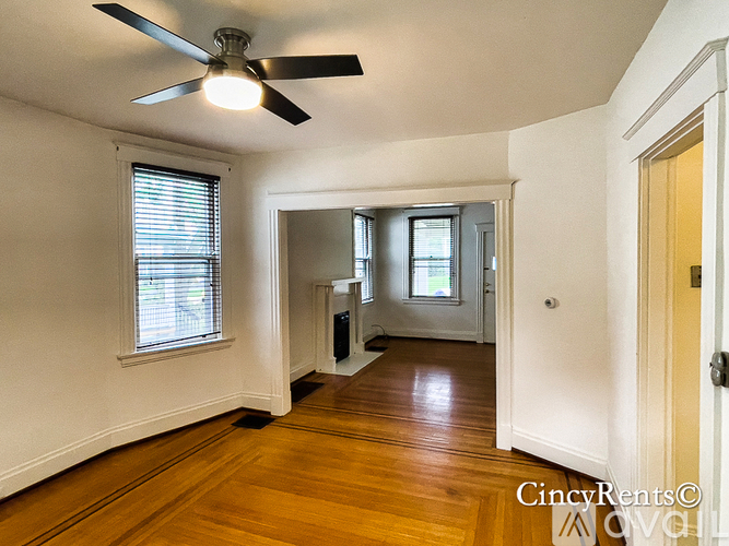 A room with a ceiling fan and wooden floors.