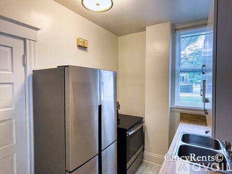 A kitchen with a stainless steel refrigerator and a black oven.