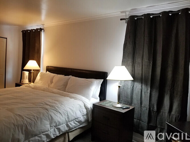 A bedroom with a large bed and two lamps on either side of the bed.