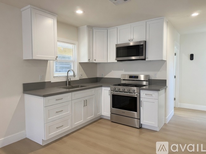 A modern kitchen with white cabinets and stainless steel appliances.