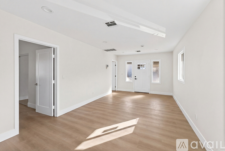 A spacious room with wooden floors and white walls.