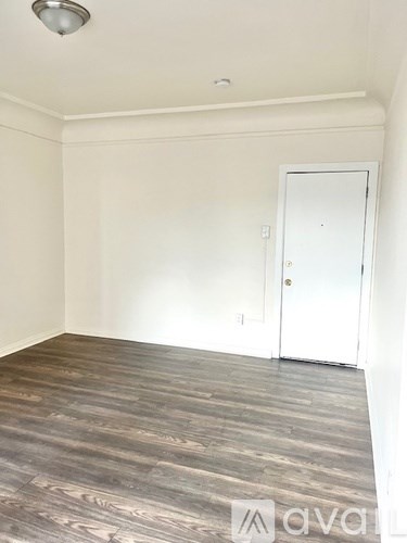 A room with a white door and wooden flooring.